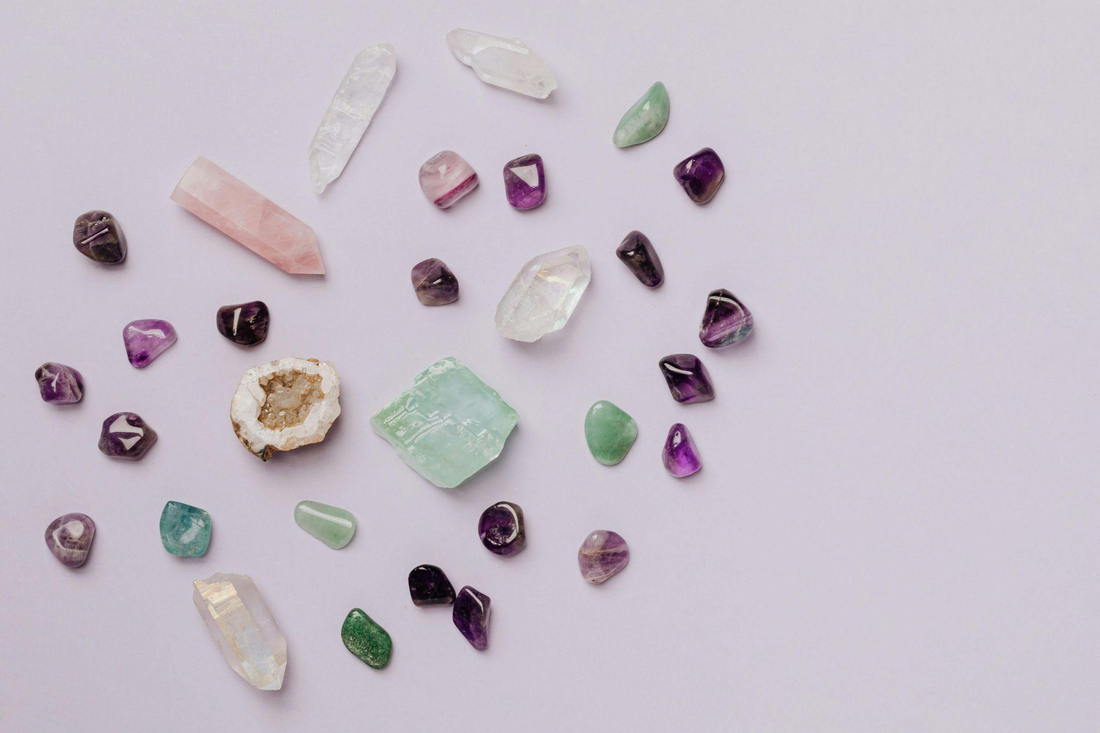 Assorted loose gemstones in multiple colors arranged on a light surface
