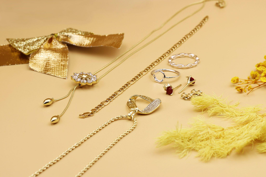 gold necklaces, rings, and earrings arranged on a warm beige surface