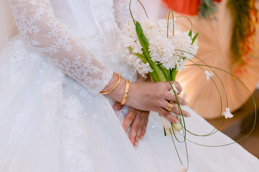 Bride holding a white flower bouquet while wearing gold bracelets