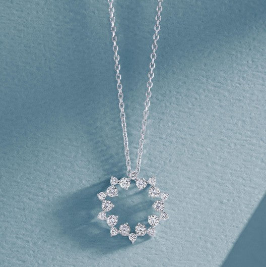 A silver diamond circle pendant necklace on a delicate chain